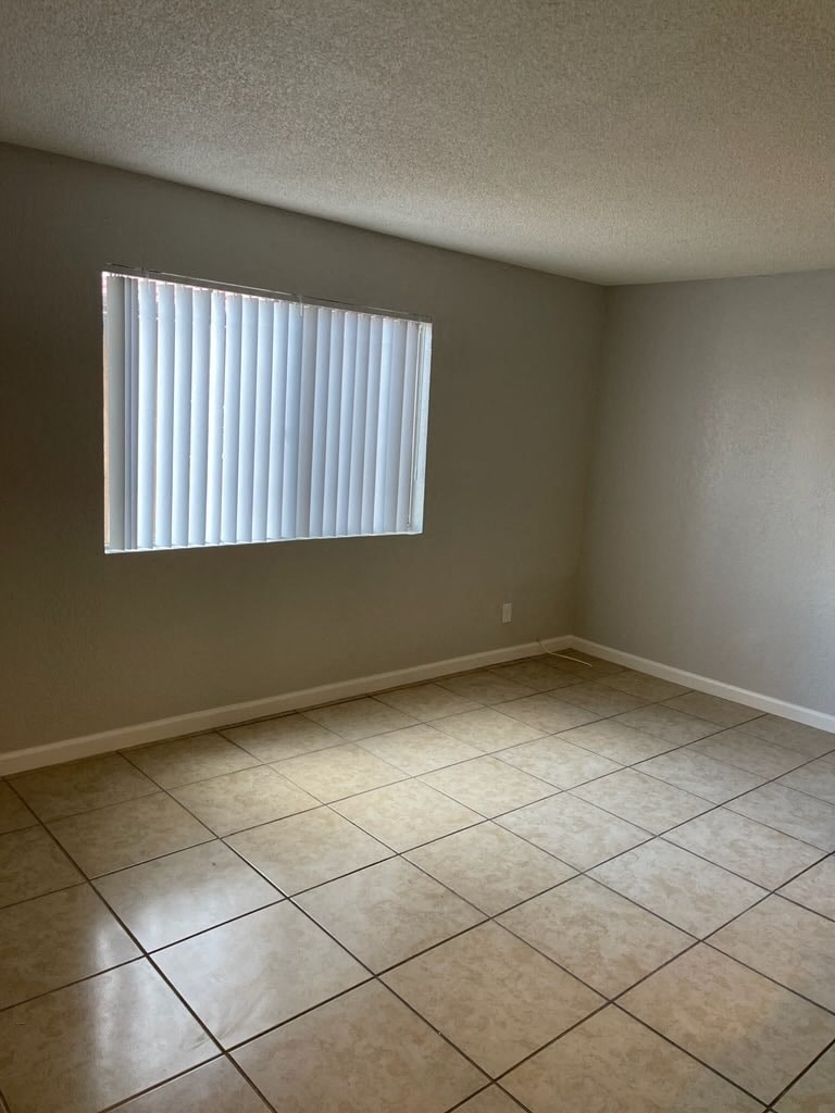 an empty room with a window and a tiled floor