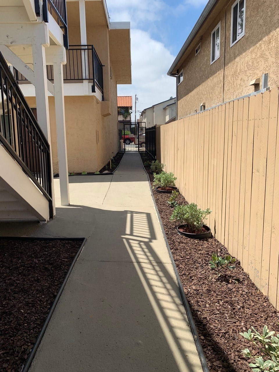 a walkway between two buildings with a wooden fence