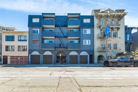 A blue building with a black car parked in front.