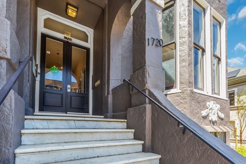 The front steps of a building with a black door and a sign that reads "1720".