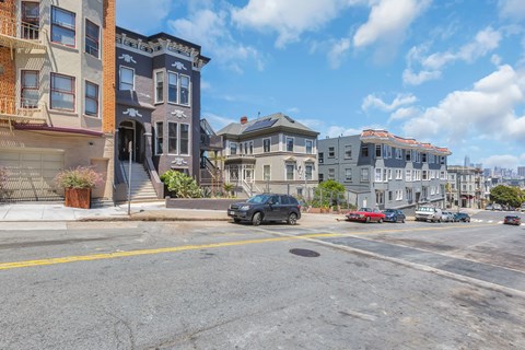 A street view with buildings on the side and cars parked on the side of the road.
