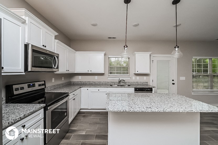 a kitchen with white cabinets and granite counter tops