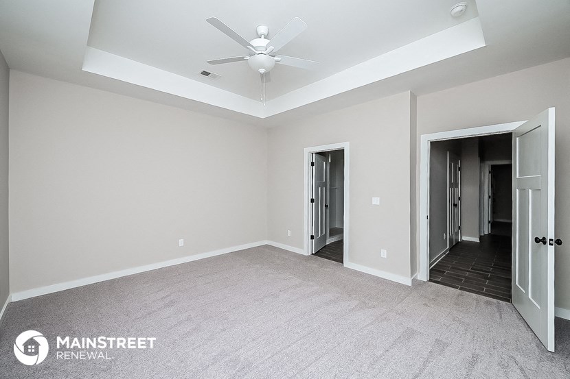 the master bedroom has a ceiling fan and carpeted flooring