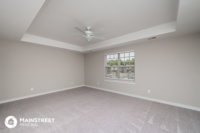 the spacious living room with ceiling fan and window