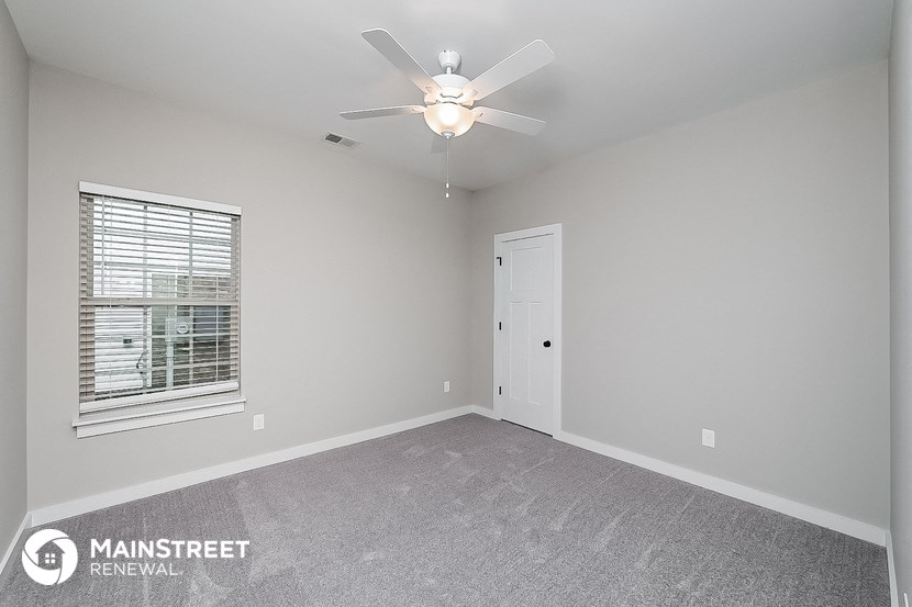 the spacious living room with ceiling fan and window
