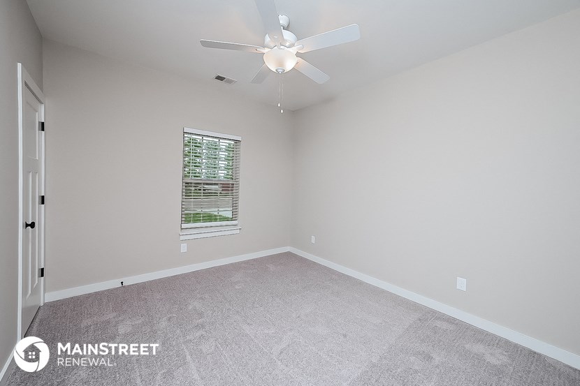 the spacious living room with ceiling fan and carpeting