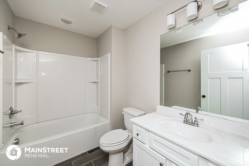a white bathroom with a white sink and toilet and a shower