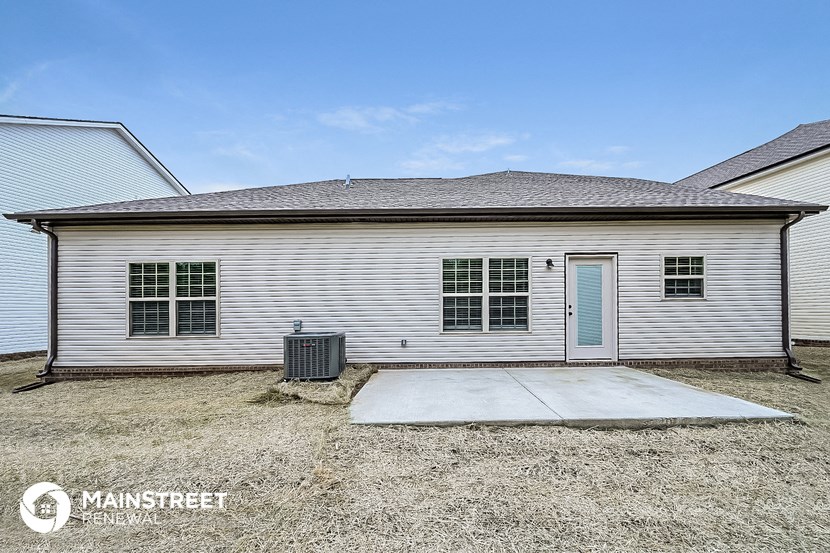 a side view of a white house with a driveway and a blue door
