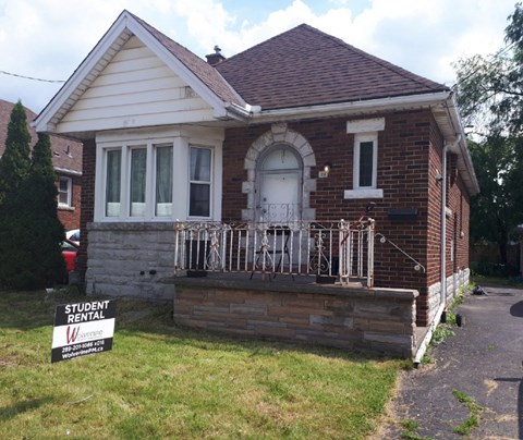 a small brick house with a street sign in front of it