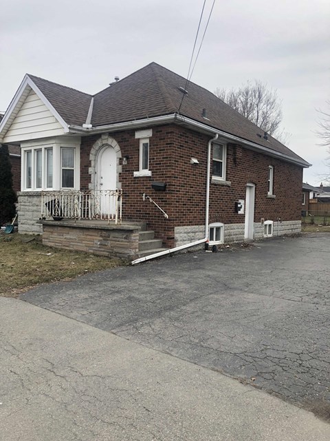 the front of a brick house with a porch and stairs
