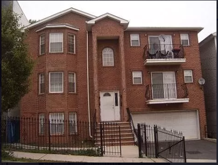 A red brick house with a white door and black iron fence.