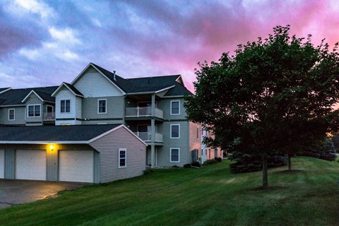 a house on a hill with a pink sunset behind it