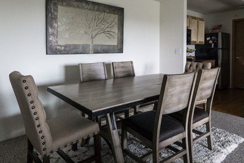 a dining room table with chairs and a painting on the wall