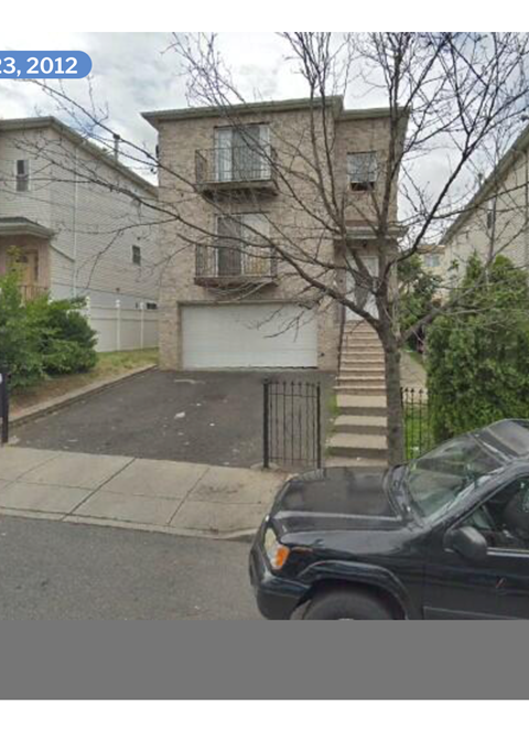 A black car is parked in front of a house.