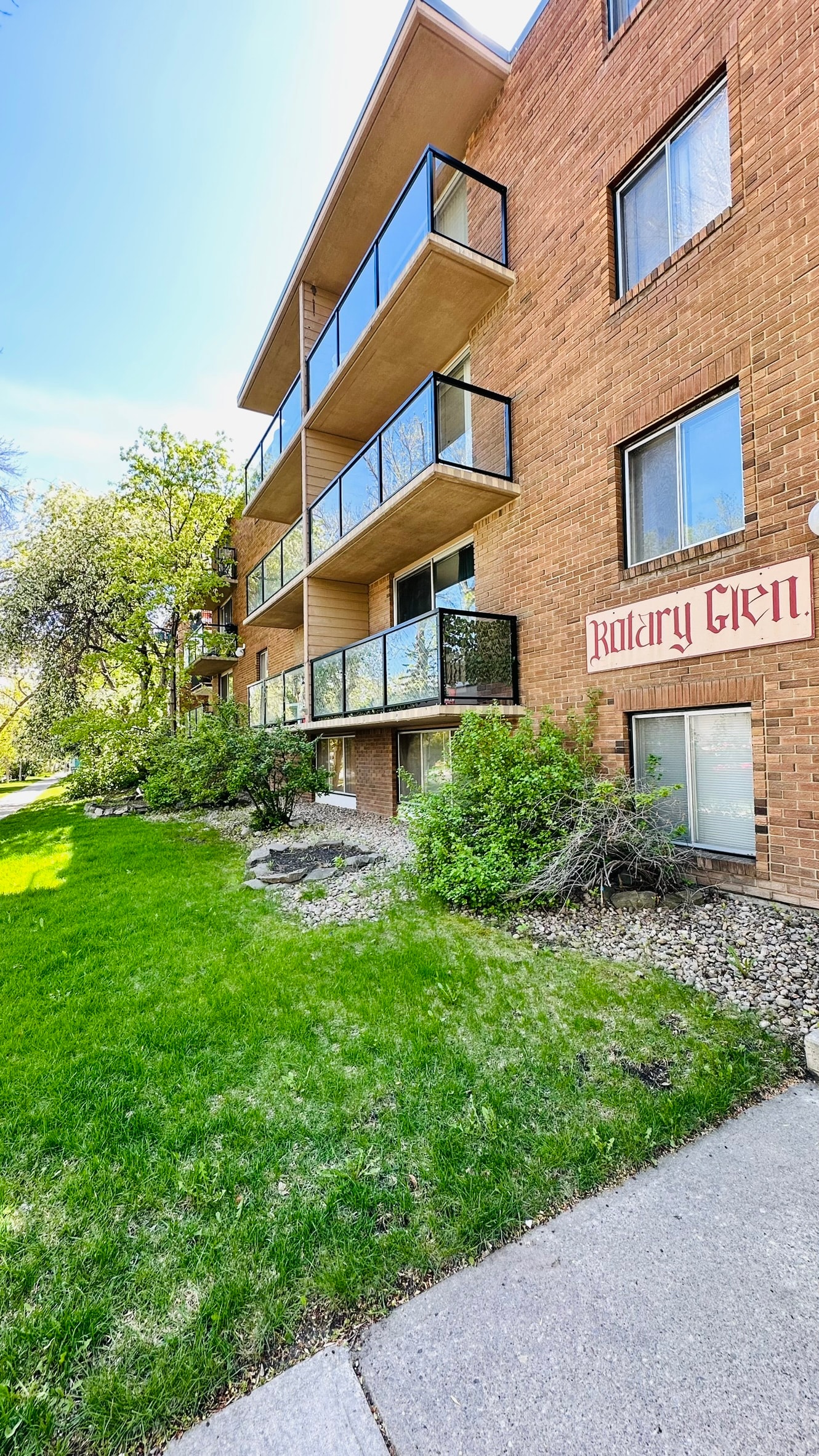 a brick apartment building with a green yard in front of it