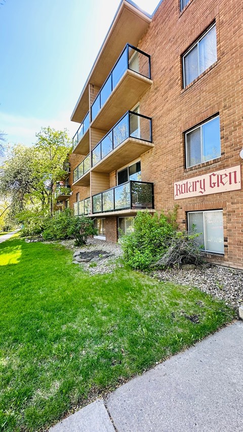 a brick apartment building with a green yard in front of it