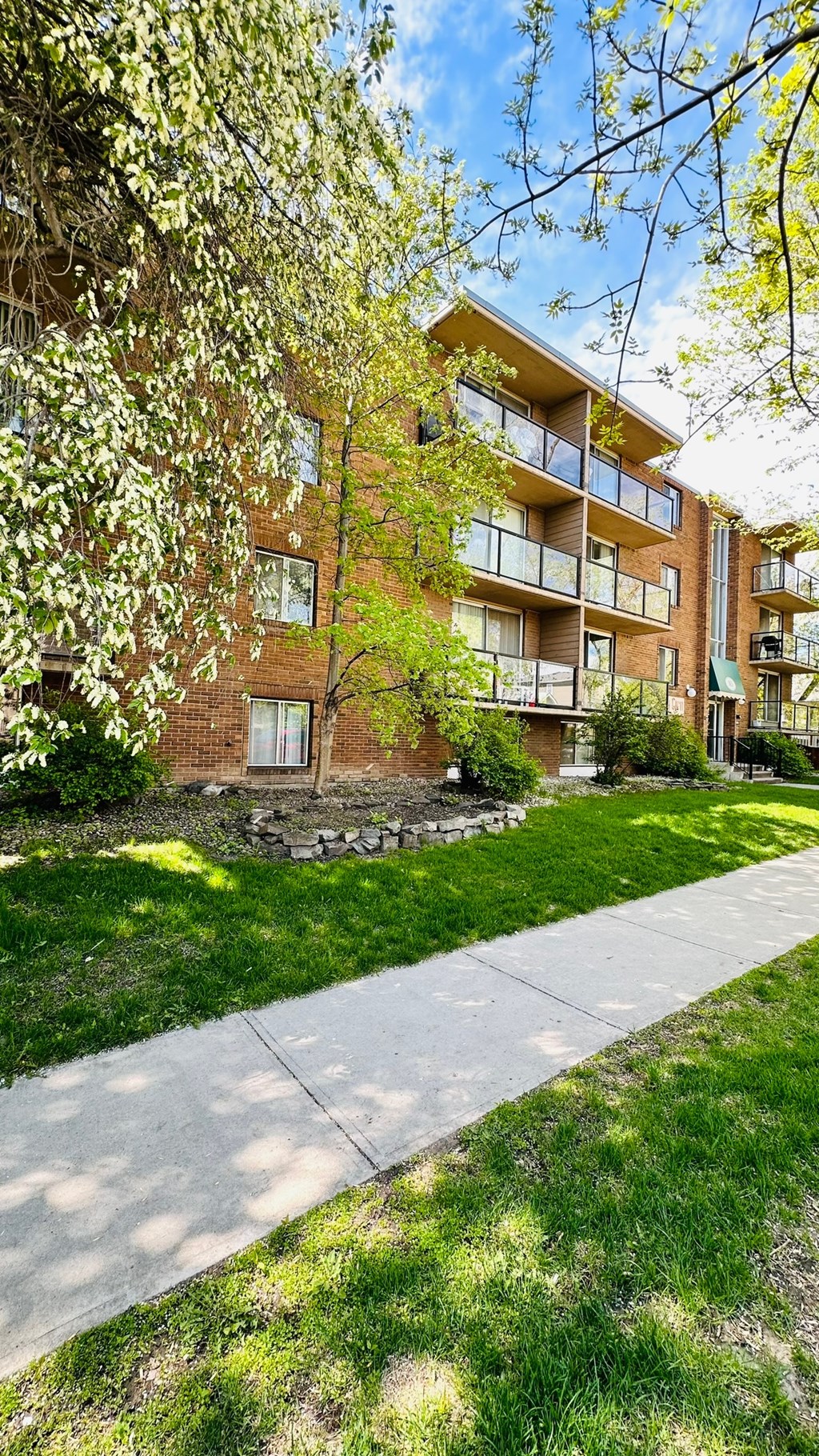 a brick apartment building with a sidewalk in front of it