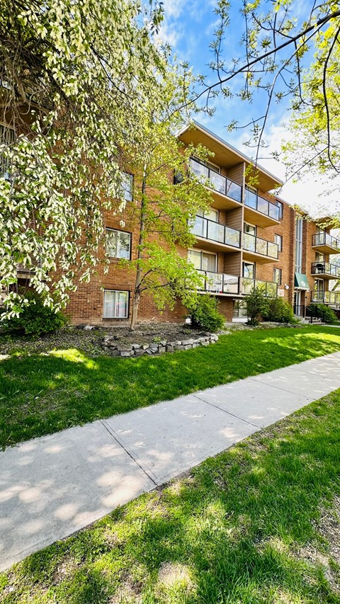 a brick apartment building with a sidewalk in front of it
