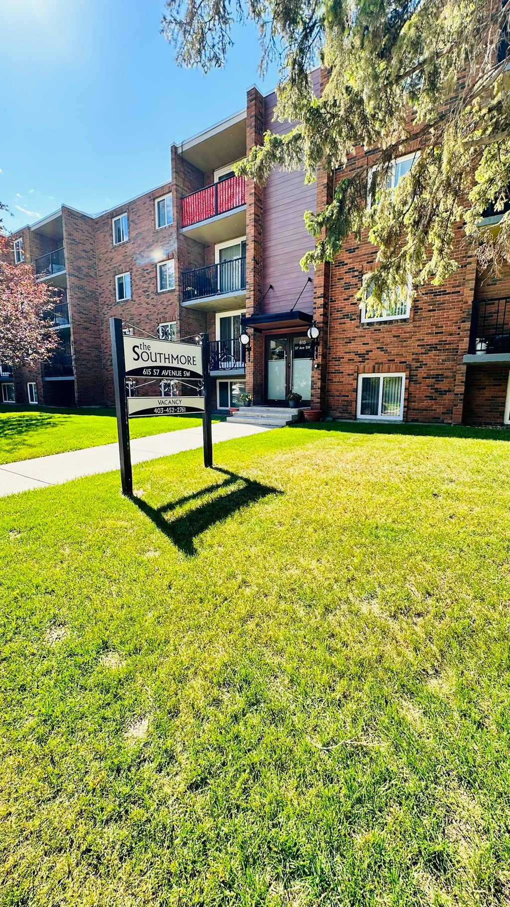 a sign in the grass in front of an apartment building