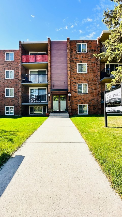 a walkway in front of a brick building with a sidewalk and grass