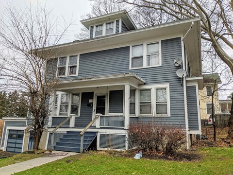 A blue two-story house with a white door and windows.