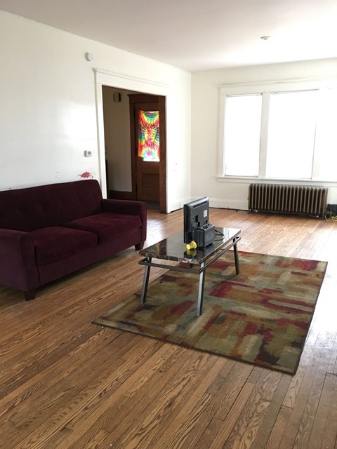A living room with a red couch and a television on a stand.