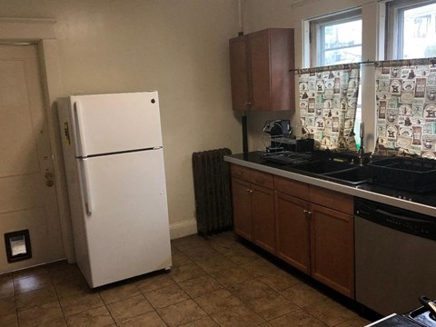 A white fridge in a kitchen with a tiled floor.