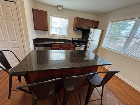 A kitchen with a granite countertop and black chairs.