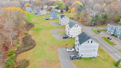 A row of houses with cars parked in front.