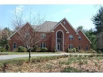A red brick house with a tree in front.