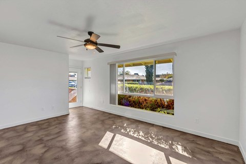 a living room with a large window and a ceiling fan