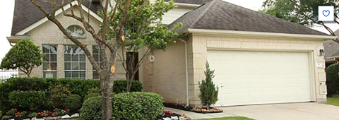 A house with a white garage door and a tree in front.