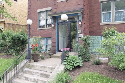 the front of a brick building with steps and a garden