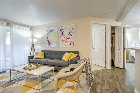 A living room with a grey couch and a glass coffee table.