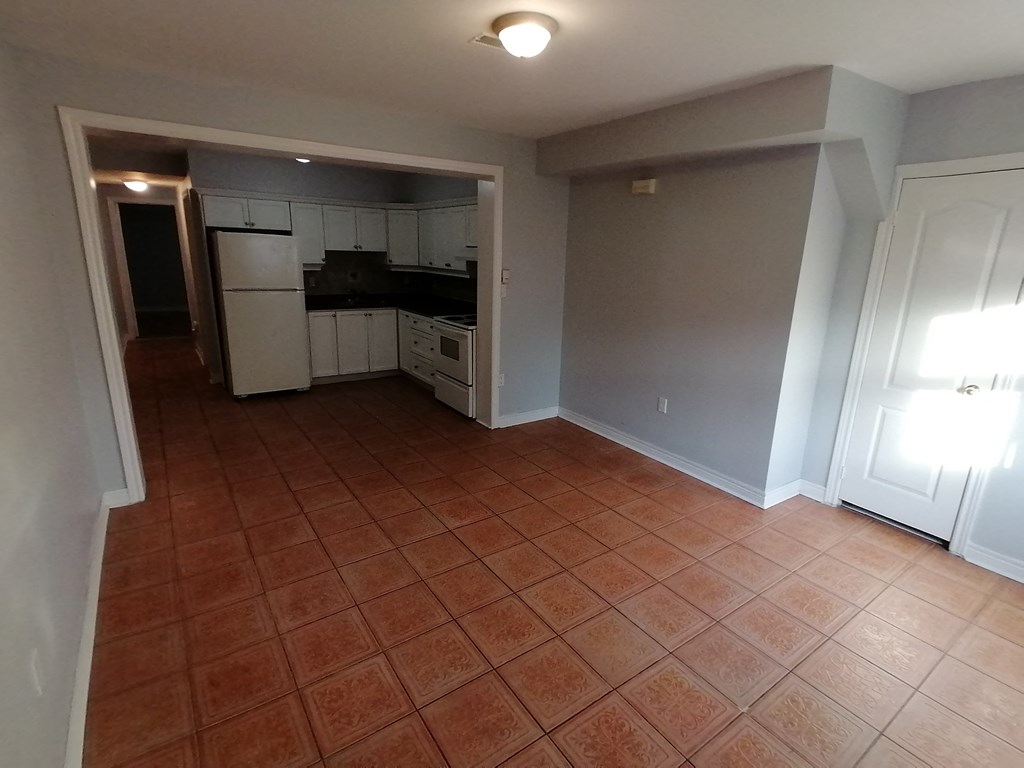 an empty kitchen and living room with a tiled floor