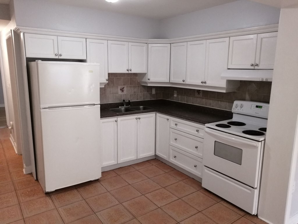 an empty kitchen with white appliances and white cabinets