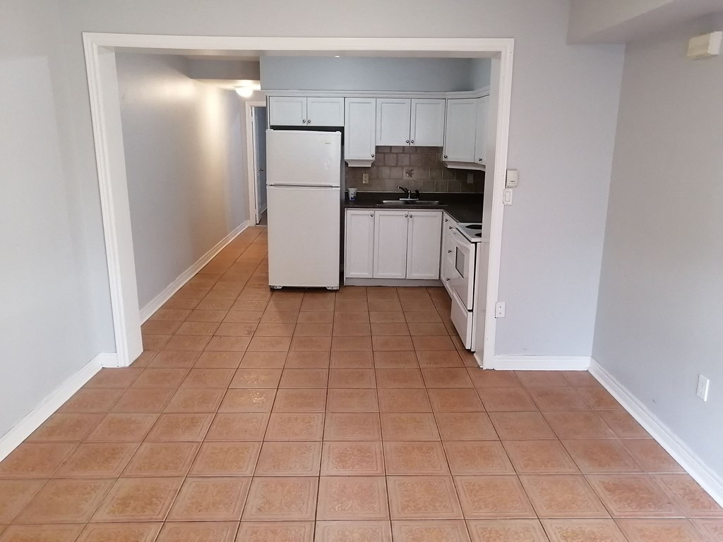 an empty kitchen with white appliances and white cabinets