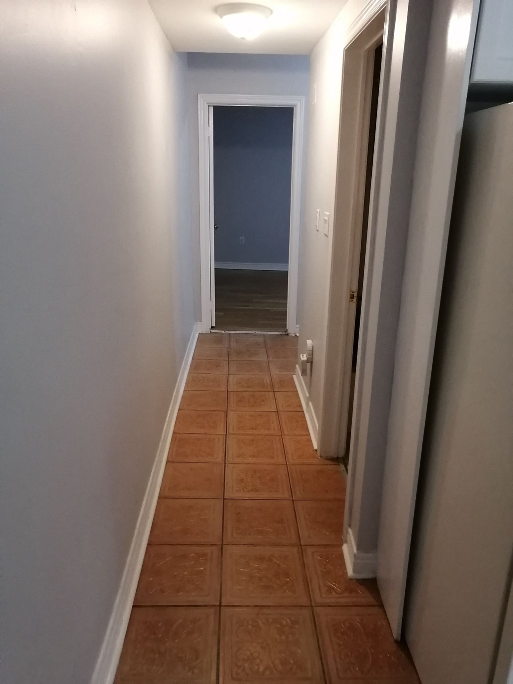 a hallway with a tiled floor and a blue wall and a door