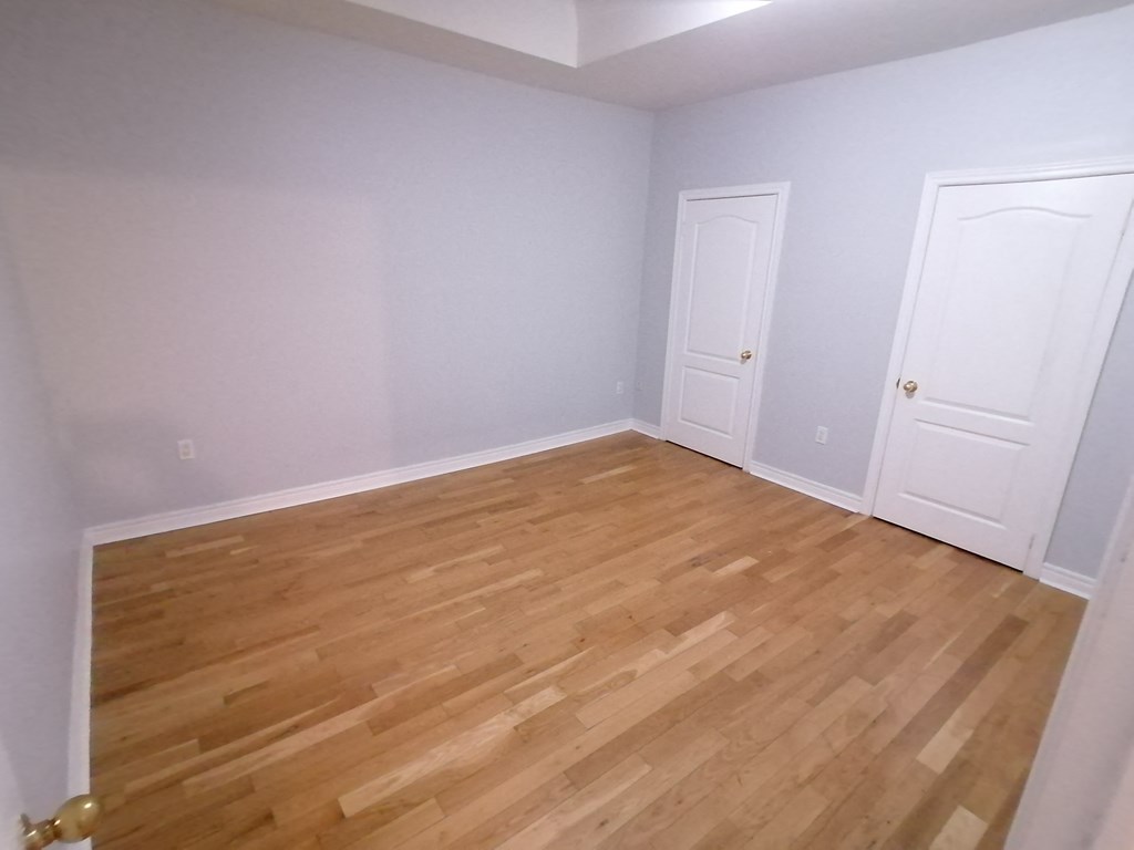 an empty room with wooden floors and two doors