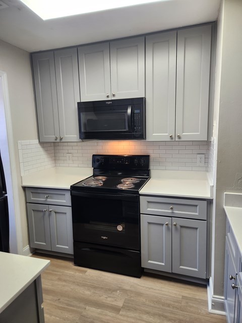 A black stove in a kitchen with white cabinets.