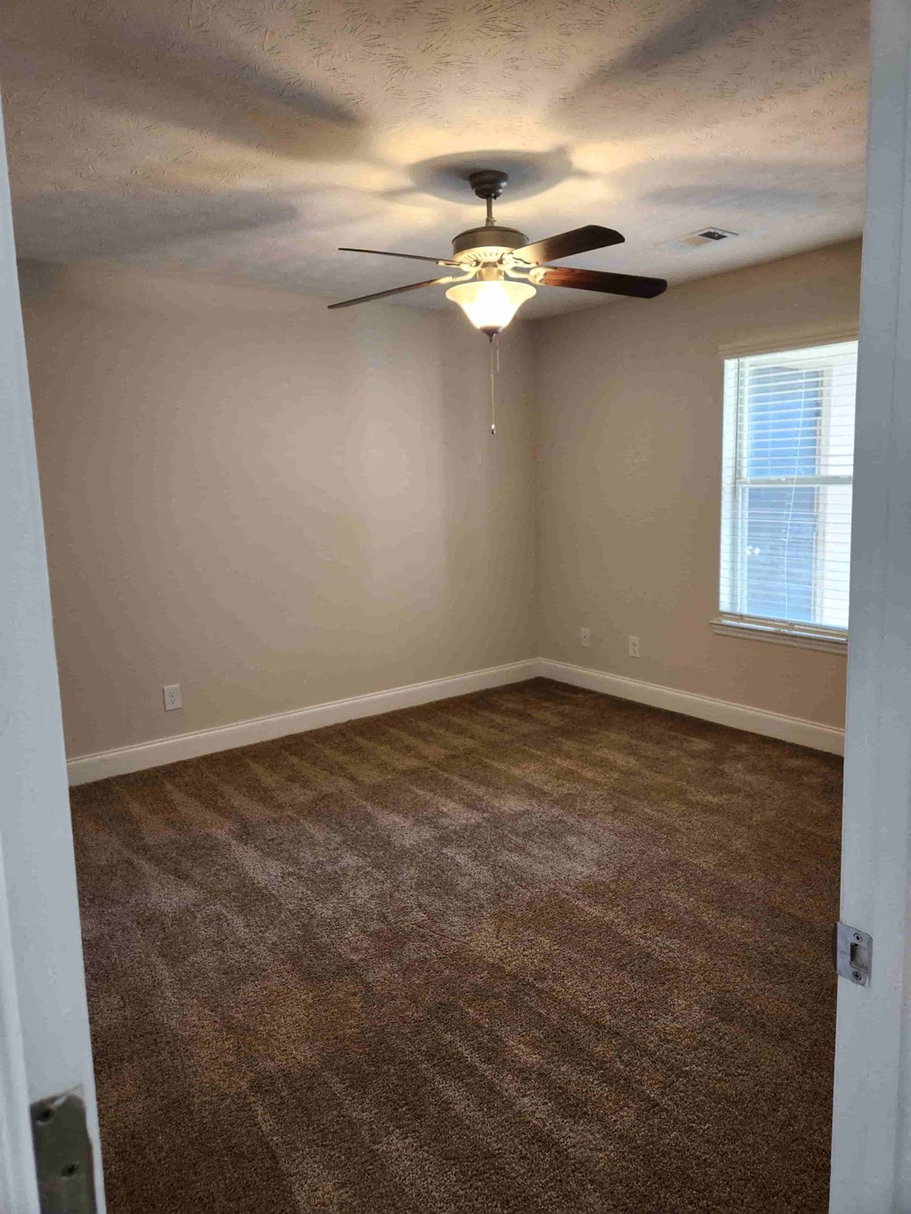 A room with a ceiling fan and carpeted floor.