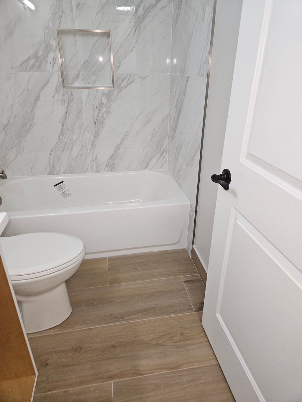 a bathroom with a toilet and a tub and a door