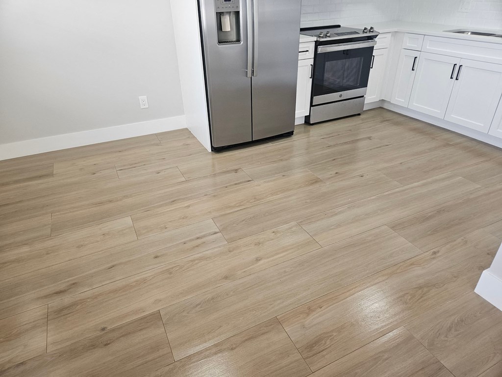 a kitchen with hardwood floors and a stainless steel refrigerator