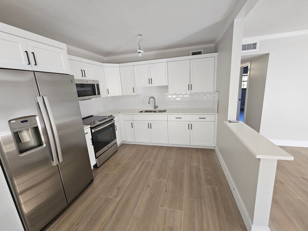 a renovated kitchen with white cabinets and stainless steel appliances