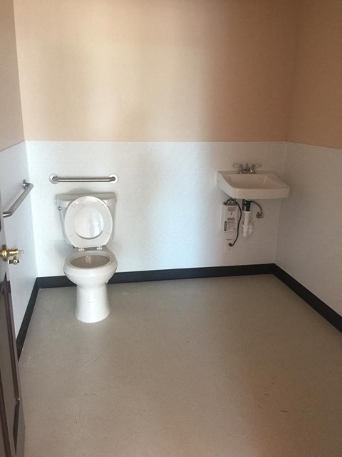 A white toilet in a small bathroom with a sink and a towel rack.