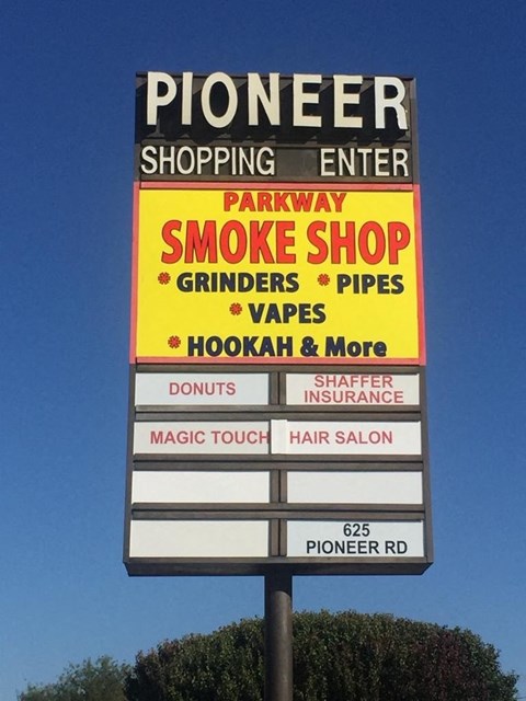 A sign for Pioneer Shopping Center lists the businesses located within.