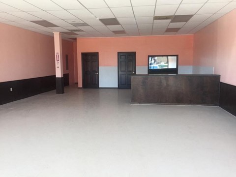 A room with a television on a stand and two doors.