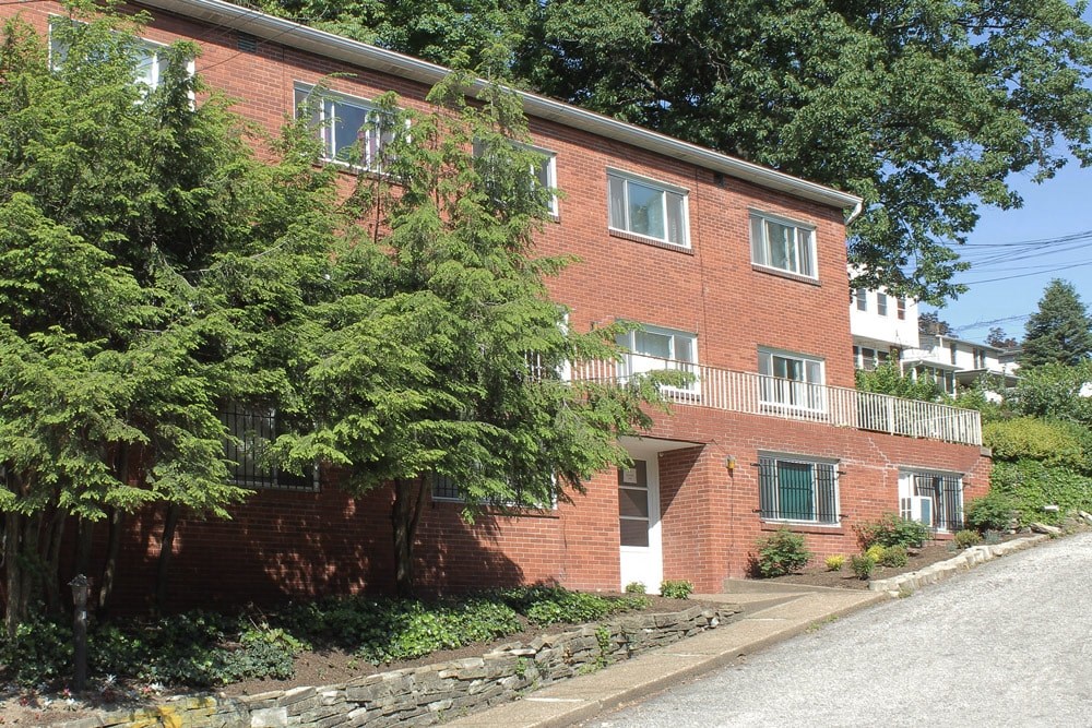 A red brick building with green trees in front.