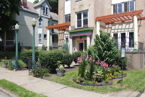 the front yard of an apartment building with a flower garden