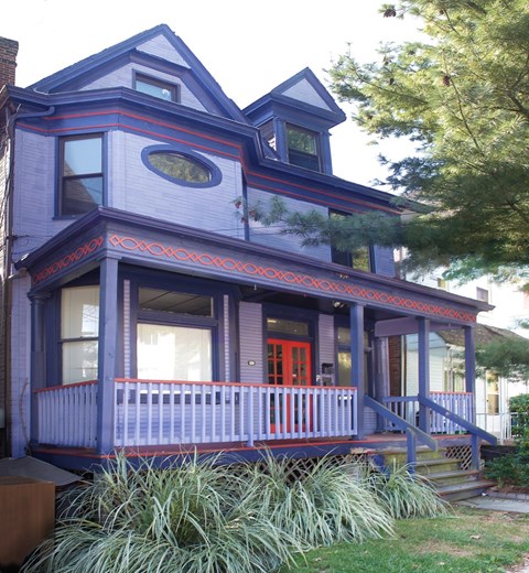 A blue house with a red door and a balcony.